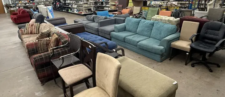 Used sofas and chairs under the Furniture sign at Bargain Thrift Store