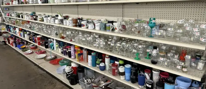 Glassware, mugs and tumblers on shelves at Bargain Thrift Store